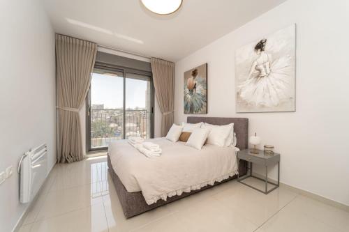 um quarto branco com uma cama grande e uma janela em Luxury Harav Agan 3 Bd apt em Jerusalém