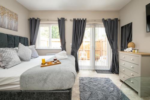 a bedroom with a bed and a dresser and windows at Willow Lodge Apartment in Solihull