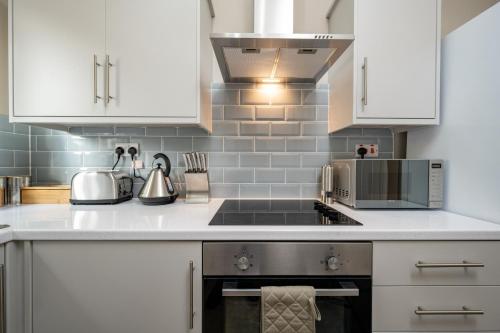 a kitchen with white cabinets and a stove top oven at Willow Lodge Apartment in Solihull