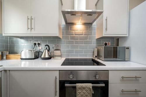 a kitchen with white cabinets and a stove top oven at Blossomfield Serviced Apartment, Solihull, Near NEC and Airport in Solihull