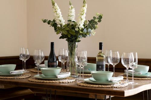 a table with a vase of flowers and wine bottles at Central Llanrwst apartment ~ Perfect for walkers and MTB riders in Llanrwst