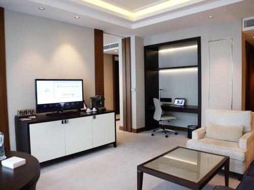 a living room with a tv and a couch and a chair at Hilton Istanbul Bomonti in Istanbul
