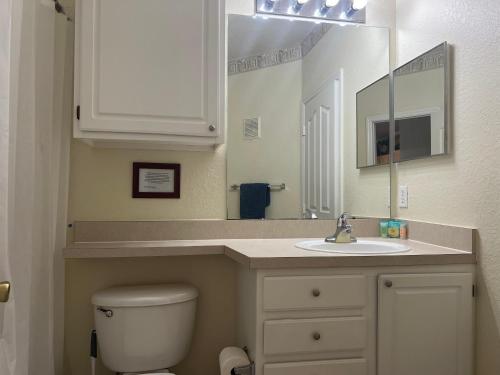 een badkamer met een toilet, een wastafel en een spiegel bij Luxury Apartment near Disney and other Theme parks in Kissimmee