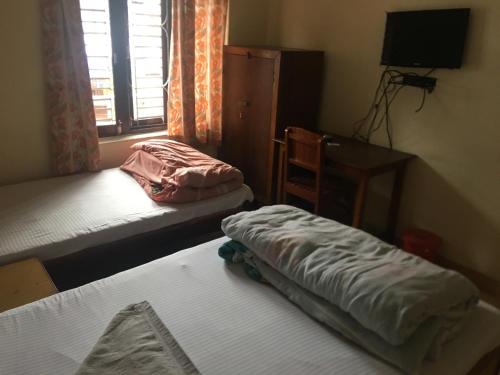 a room with two beds and a desk and a window at New ELITE’S Guest House in Pokhara