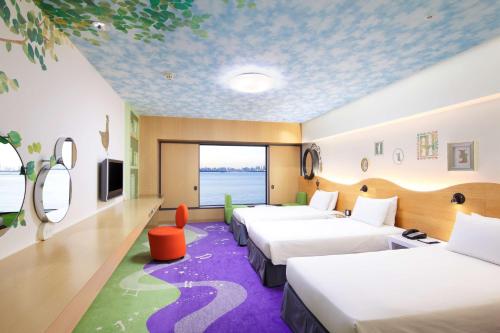 a hotel room with three beds and a large window at Hilton Tokyo Bay in Urayasu