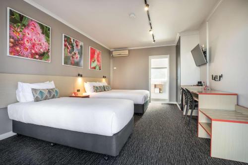 una camera d'albergo con due letti e una scrivania di Nightcap at Ferntree Gully Hotel Motel a Fern Tree Gully
