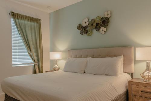 um quarto com uma cama com lençóis brancos e 2 candeeiros em Heated Pool Vacation Villa, Theme Room, Gated Community near Disney, Sleeps 12! em Kissimmee
