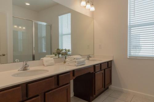 a bathroom with a sink and a large mirror at Heated Pool Vacation Villa, Theme Room, Gated Community near Disney, Sleeps 12! in Kissimmee