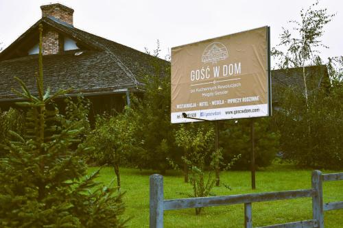a sign in front of a house with a building at Hotel Gość w dom 