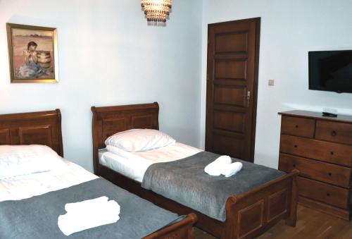 a bedroom with two beds and a tv and a dresser at Hotel Gość w dom 