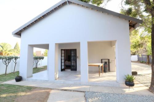 a white house with a table in a yard at Boom on Vaal in Parys