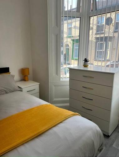 um quarto com uma cama, uma cómoda e uma janela em spacious 3 bed - EFC stays em Liverpool