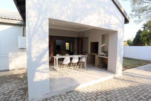 a white house with a patio with a table and chairs at Boom on Vaal in Parys