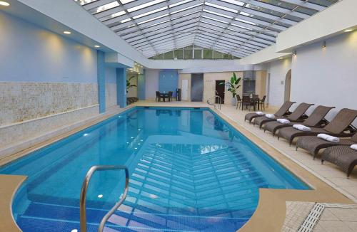 une grande piscine avec des chaises et une table dans l'établissement DoubleTree by Hilton Oxford Belfry, à Thame