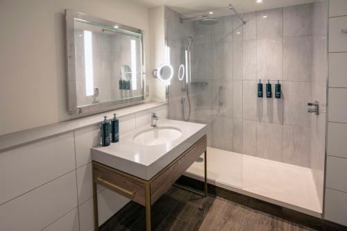 uma casa de banho com um lavatório e um chuveiro em DoubleTree by Hilton Oxford Belfry em Thame
