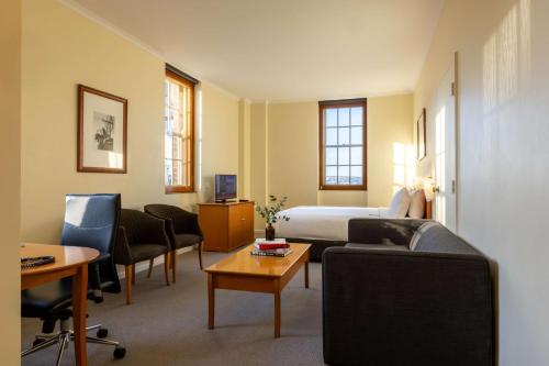 Sydney Harbour Hotel في سيدني: غرفه فندقيه بسرير واريكه وكراسي