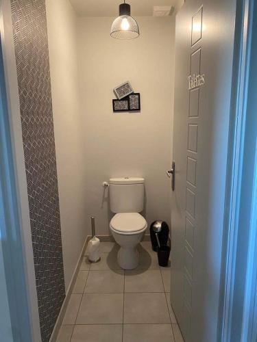 - une petite salle de bains avec des toilettes et une porte dans l'établissement Chambre les Hortensias, à Challans