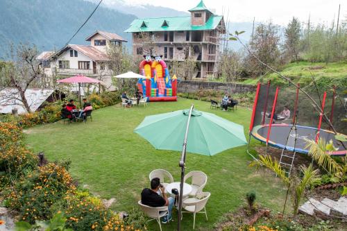 a couple sitting in chairs under an umbrella in a yard at Hotel Smugglers Mountain View - central heated & air Cooled in Manāli