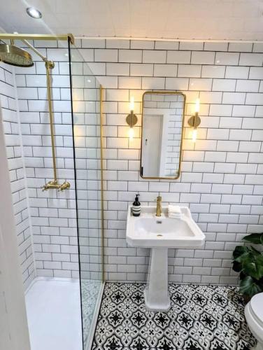 ein Bad mit einem Waschbecken, einem Spiegel und einer Dusche in der Unterkunft The Cottage @ 59 in Colmonell