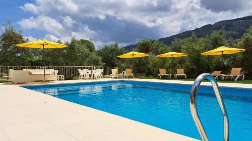 a swimming pool with yellow umbrellas and tables and chairs at Villa Carmen in Bocairent