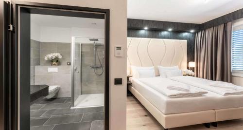 een slaapkamer met een groot wit bed en een douche bij PLAZA INN Wiener Neustadt, BW Signature Collection in Wiener Neustadt