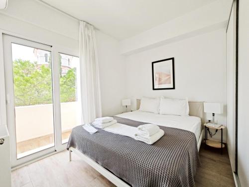 a white bedroom with a bed and a large window at Marathonomachon Apartments by Verde Apartments in Athens