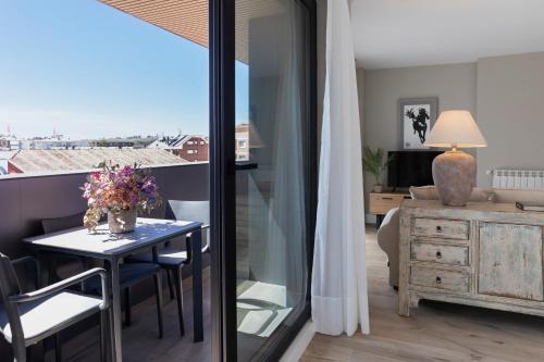 a living room with a table and a view of a room at Apartamentos Plaza Center in Suances