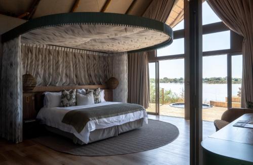 a bedroom with a large bed with a large window at Victoria Falls River Lodge in Victoria Falls