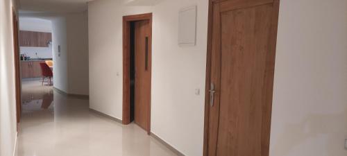 a hallway with a wooden door and a room at APPARTEMENT haut standing in O Ben Slimane