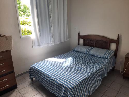 um quarto com uma cama com um edredão listrado e uma janela em Apartamento em Jacaraipe ES 3 quartos em Jacaraípe