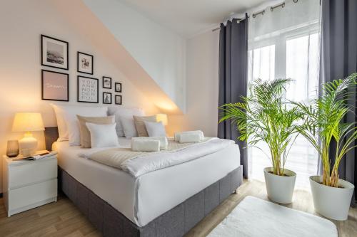 a bedroom with a white bed with two potted plants at Aparthotel Solskiego Wrocław in Wrocław