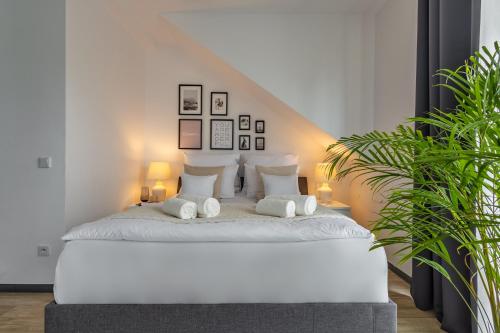 a white bedroom with a white bed with two pillows at Aparthotel Solskiego Wrocław in Wrocław