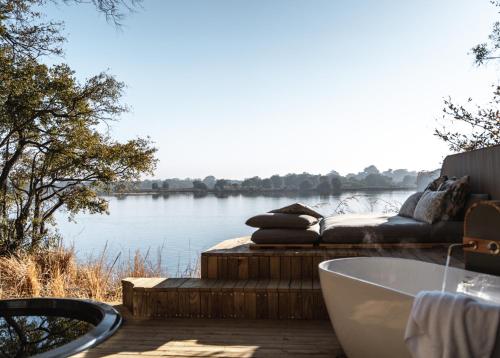 a bath tub sitting on a deck with a view of a lake at Victoria Falls River Lodge in Victoria Falls
