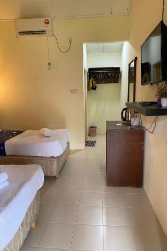 a hotel room with two beds and a tv at Corrie Chalet Pantai Cenang Langkawi in Pantai Cenang