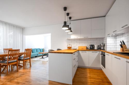 een keuken met witte kasten en een tafel en stoelen bij Contemporary Comfort: 1BD Flat in Lozenetz, Sofia in Sofia