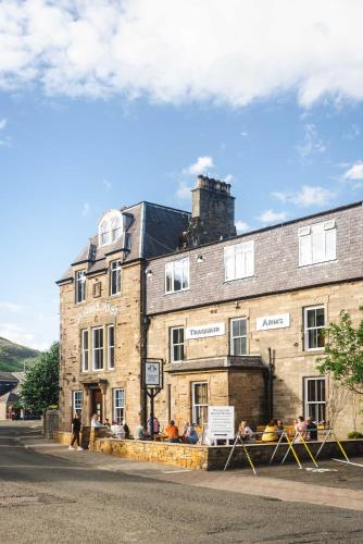 an old brick building with people sitting outside of it at Traquair Arms Hotel in Innerleithen