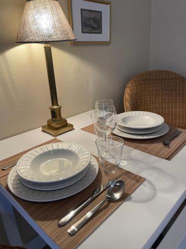 a table with plates and glasses and a lamp on it at Le 25, Duplex élégant au cœur du piétonnier historique in Namur