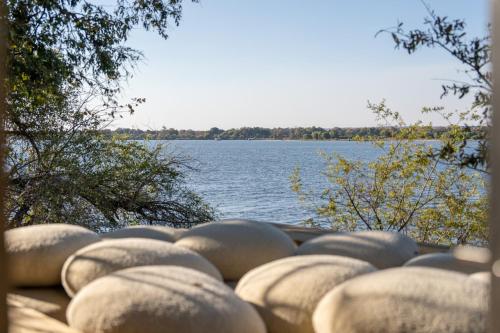 a bunch of cement balls sitting on the side of a lake at Victoria Falls River Lodge in Victoria Falls