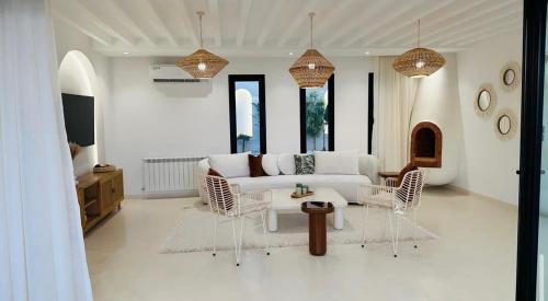 sala de estar con sofá blanco y sillas en Dar Oliva Maison de luxe, en Houmt El Souk