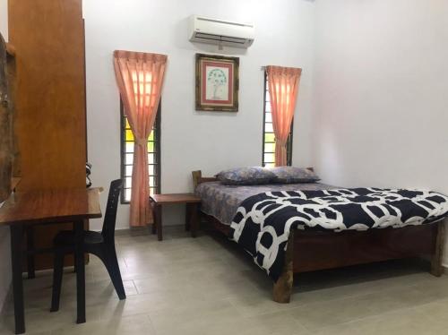 a bedroom with a bed and a desk and two windows at Laman Norras Homestay in Kepala Batas
