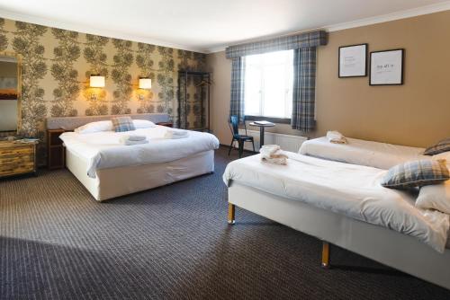 イナーリーセンにあるTraquair Arms Hotelのベッド2台とデスクが備わるホテルルームです。