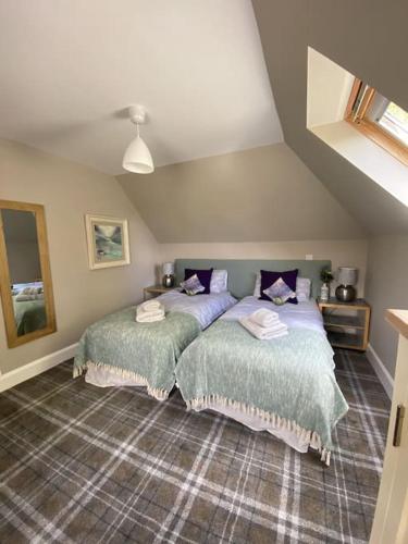 two beds in a room with a attic at Middle Lodge in Aberfeldy