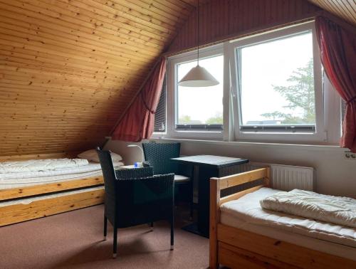 een kamer met 2 bedden en een tafel op zolder bij Aalhues-Ferienwohnung-ueber-2-Etagen-fuer-4-Erwachsene-und-1-Kind in Westerland