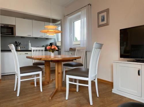 cocina y comedor con mesa y sillas en Aalhues-Ferienwohnung-ueber-2-Etagen-fuer-4-Erwachsene-und-1-Kind en Westerland