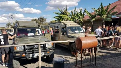 Kirubis Safari Lounge في Narok: مجموعة من الناس تقف بجوار شاحنة عسكرية