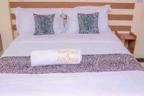 a white bed with a zebra blanket on it at Kirubis Safari Lounge in Narok