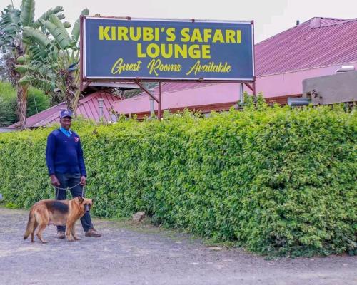 un hombre con un perro parado frente a una tienda en Kirubis Safari Lounge en Narok