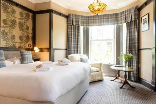 una habitación de hotel con una cama grande y una silla en Traquair Arms Hotel en Innerleithen