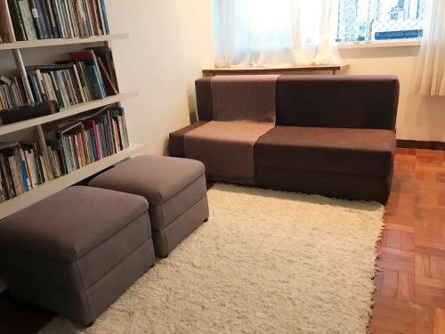 uma sala de estar com um sofá, uma cadeira e uma estante de livros em Aconchegante, ótima localização e vista para o mar no Recife