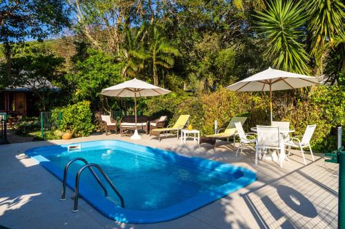 a swimming pool with tables and chairs and umbrellas at Pousada Mar de Dentro in Florianópolis